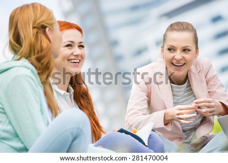 Happy young female college friends studying outdoors