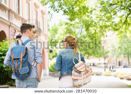Rear view of young college friends talking while walking in campus