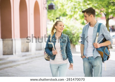 Young college friends talking while walking at campus