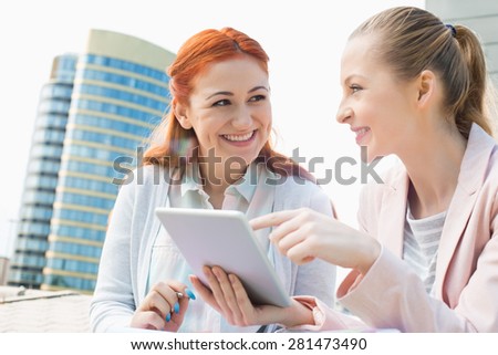 Smiling young university students using tablet PC against building