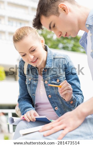 Young woman with male friend studying together at college campus
