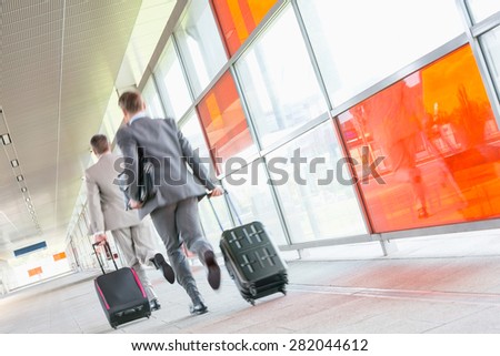 Rear view of middle aged businessmen with luggage rushing on railroad platform