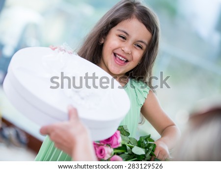 Portrait of cute girl holding gift box and flower basket at home