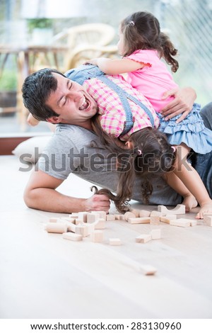 Playful daughters on top of father at home
