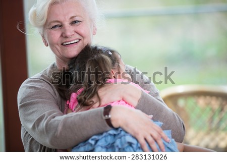 Portrait of happy grandmother hugging granddaughter in house