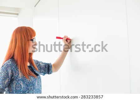Businesswomen writing on whiteboard in creative office