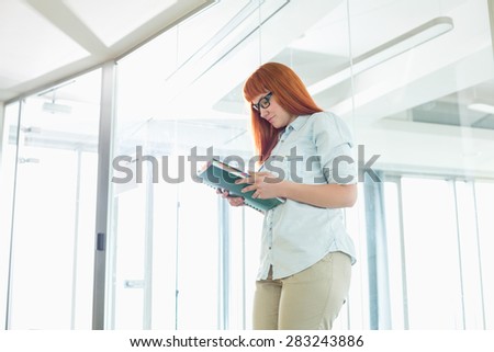 Creative businesswoman reading file in office