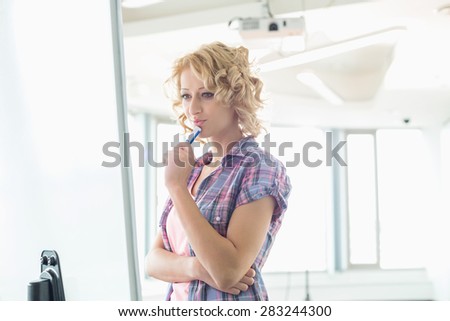 Concentrated businesswoman looking at presentation board in creative office