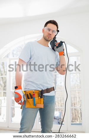 Confident mid-adult man with drill in new house