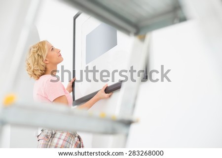 Woman positioning picture frame on wall