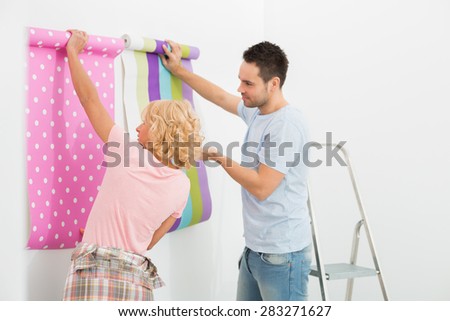 Couple holding up wallpaper samples in new house