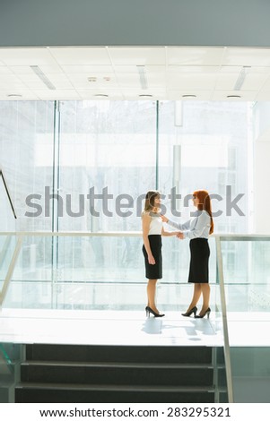 Full-length of businesswomen shaking hands at office hallway