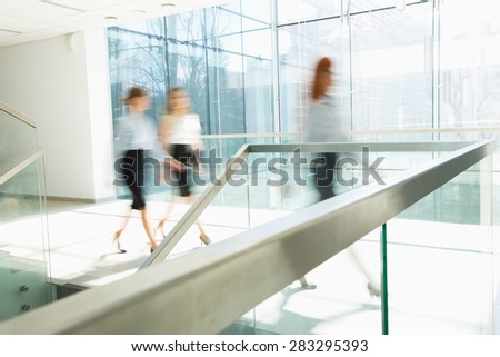 Blurred motion of businesswomen walking at office hallway