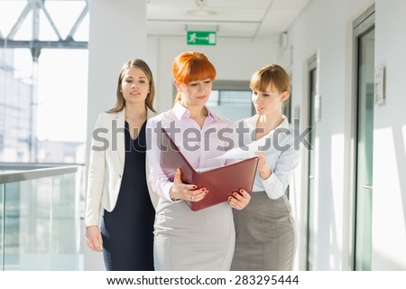 Businesswomen discussing over documents at office hallway