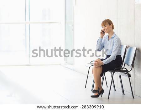 Businesswoman using cell phone while sitting on chair in office