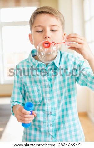 Cute boy playing with bubble wand at home