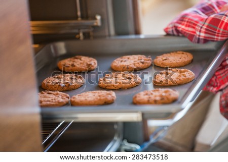 Cropped image of hand removing cookie tray from oven in kitchen