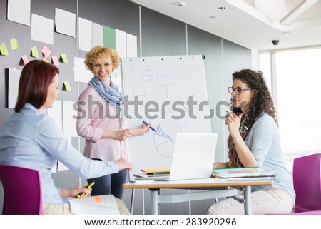 Businesswoman explaining pie chart to colleagues in creative office