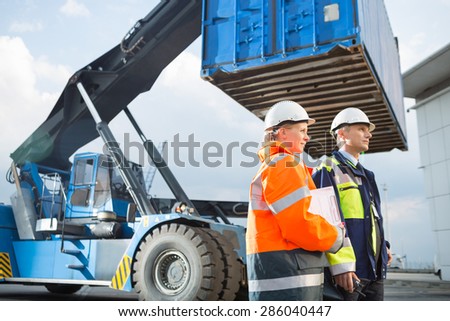 Male and female workers standing by freight vehicle in shipping yard