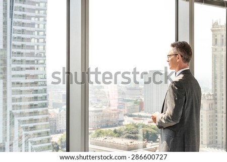 Side view of mature businessman looking through office window