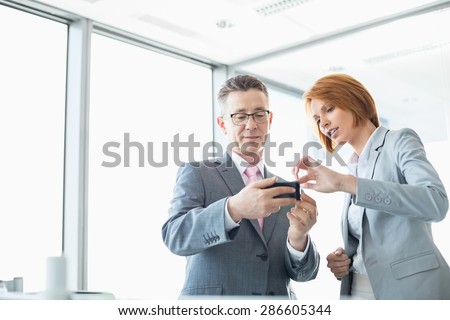 Businessman and businesswoman using cell people in office