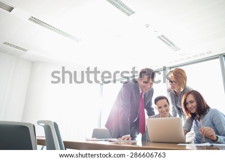 Businesspeople using laptop at conference table