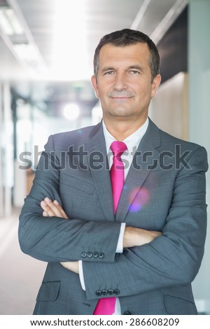 Portrait of middle-aged businessman standing with arms crossed in office