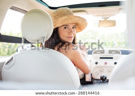 Beautiful woman looking back while driving car