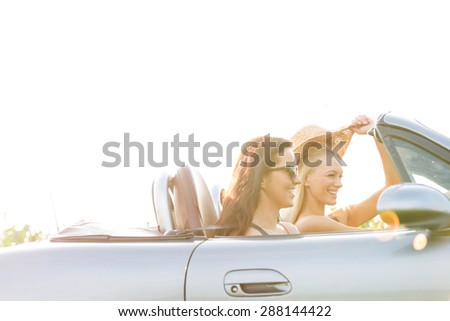 Happy female friends enjoying road trip in convertible against clear sky