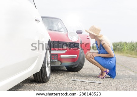 Full-length side view of tensed woman looking at damaged cars on road