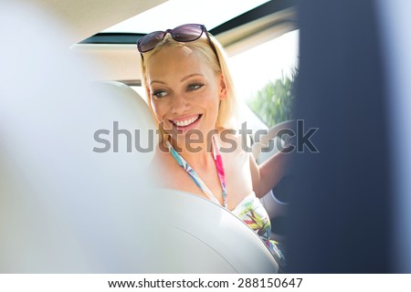 Happy beautiful woman looking back while driving car