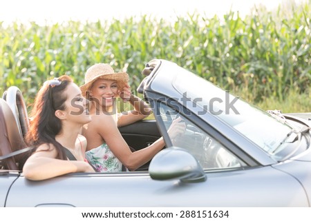 Happy female friends enjoying road trip in convertible