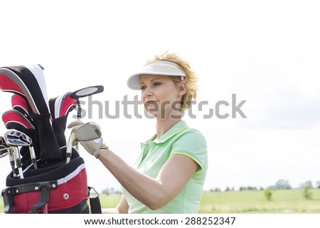 Female golfer with golf club bag against clear sky