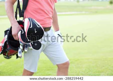 Midsection of man carrying golf club bag at course