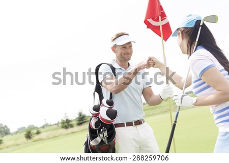 Male and female friends giving high-five at golf course