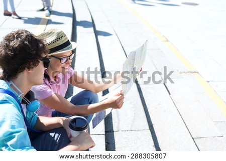 Happy couple reading map while sitting on steps outdoors