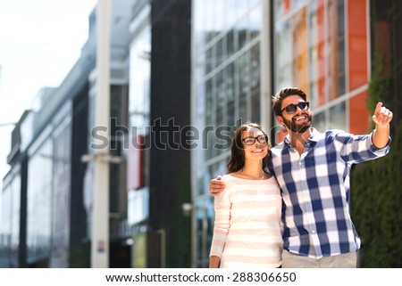 Happy man showing something to woman outside building