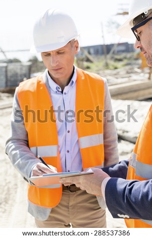 Engineers writing on clipboard at construction site