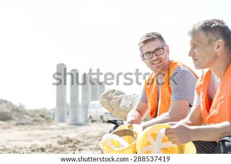 Smiling supervisor sitting with colleague at construction site