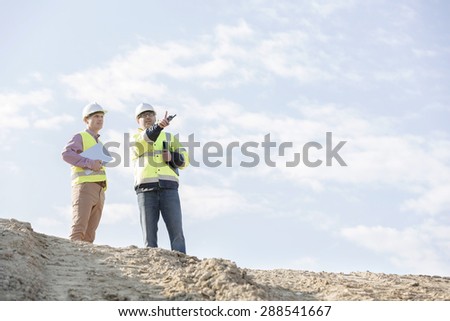 Low angle view of supervisors discussing at construction site against sky