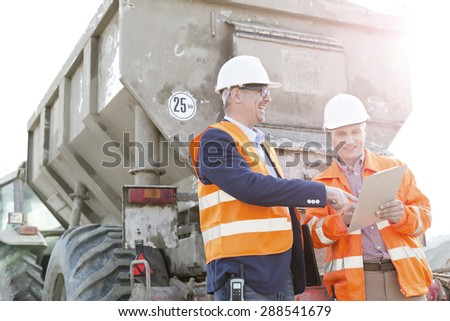 Happy architects discussing over clipboard by construction truck