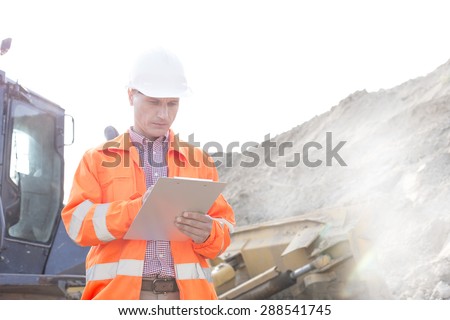 Engineer reading clipboard at construction site