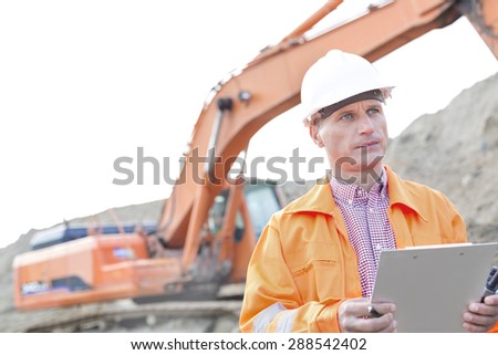 Supervisor looking away while holding clipboard at construction site