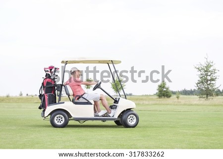 Side view of couple sitting in golf cart against clear sky