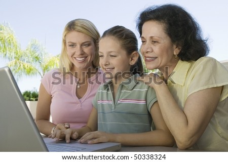 Grandmother and Mother Watching Girl Using Laptop