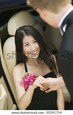 Well-dressed teenager girl being helped out of limo by date