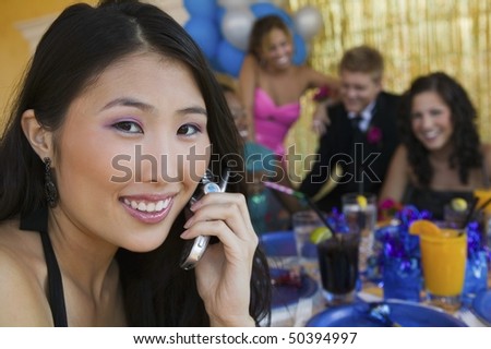 Well-dressed teenager girl using cell phone at school dance