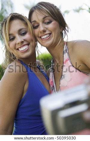 Well-dressed teenage girls taking picture outside school dance, low angle view