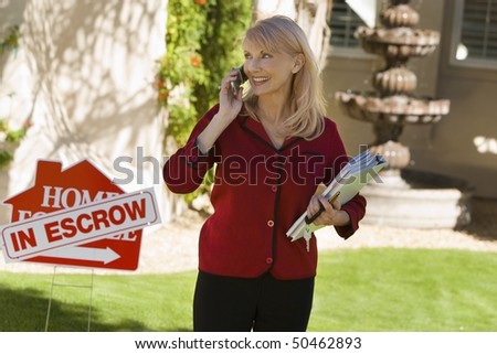Estate agent using mobile phone at in front yard of house, portrait