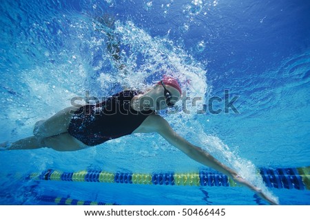 Female swimmer racing underwater in pool